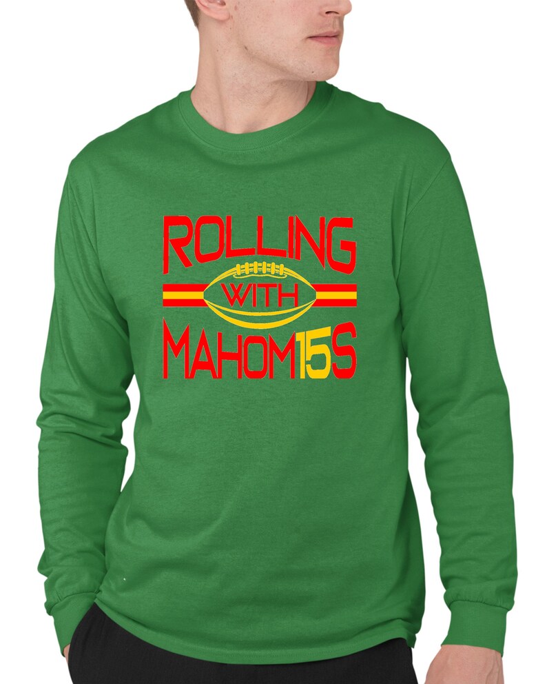 May include: Green long-sleeve t-shirt with red and yellow text that reads "Rolling with Mahomes 15" and a football graphic.