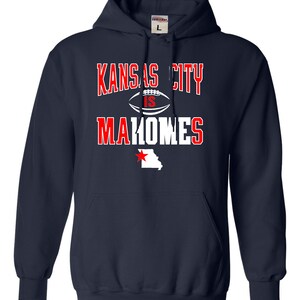 Puede incluir: Sudadera con capucha azul marino con texto blanco que dice "Kansas City is Mahomes" y un contorno blanco del estado de Misuri con una estrella roja.