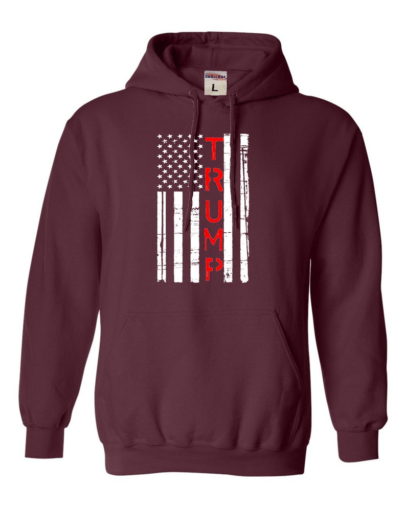 May include: A maroon hooded sweatshirt with a distressed American flag design and the word "TRUMP" printed vertically in red.