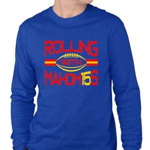 May include: A royal blue long-sleeved t-shirt with the text "Rolling with Mahomes 15" in red and yellow.