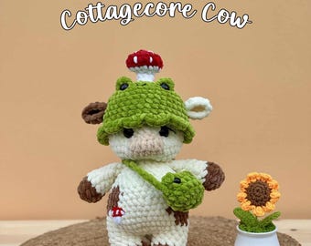 May include: A crochet cow plushie wearing a green frog hat with a small red and white mushroom on top. The cow has brown patches, a small green crossbody bag, and a tiny mushroom patch. Next to it is a small potted crochet sunflower.