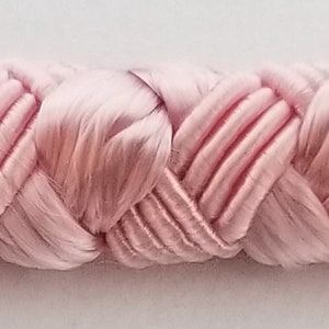 May include: Pink braided trim with a woven, heart-shaped design. This trim is perfect for adding a touch of elegance to any project.