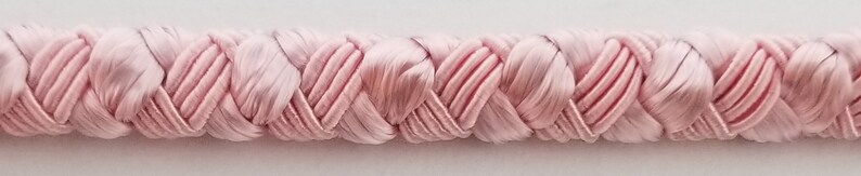 May include: Pink braided trim with a woven, heart-shaped design. This trim is perfect for adding a touch of elegance to any project.