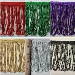 May include: Assortment of 10 yards of fringe trim in various colors, including red, green, purple, gold, silver, and black. The fringe is approximately 1 inch wide and has a metallic sheen.