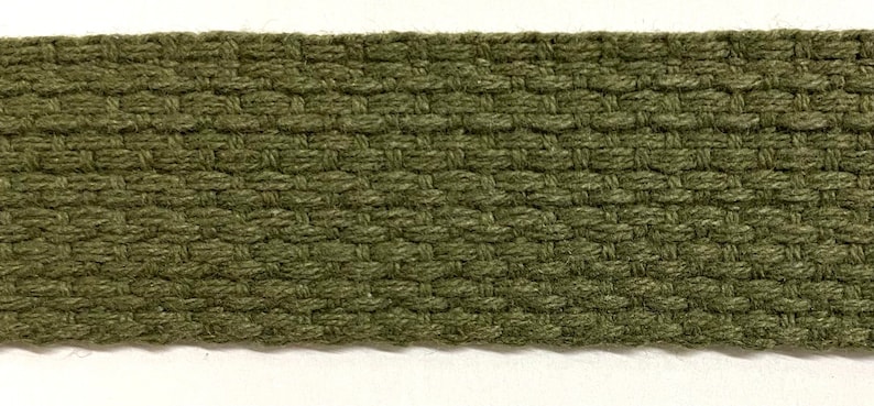May include: Close-up of a green woven fabric ribbon. The ribbon has a textured, diamond-shaped pattern.