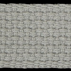 May include: A close-up of a gray woven fabric with a diagonal pattern. The fabric has a rough texture and is made of natural fibers.