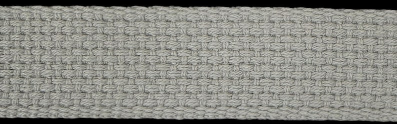 May include: A close-up of a gray woven fabric with a diagonal pattern. The fabric has a rough texture and is made of natural fibers.