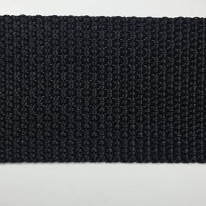 May include: Black woven webbing strap. The strap is made of a tightly woven fabric with a smooth, even texture.