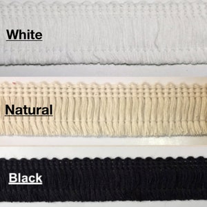 May include: Three samples of fringe trim in white, natural, and black. The fringe is a woven fabric with a scalloped edge and a fringe of short threads.