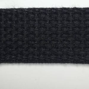 May include: A close-up of black woven webbing, a type of fabric often used for straps and belts.