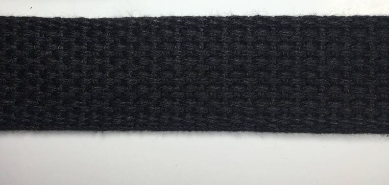 May include: A close-up of black woven webbing, a type of fabric often used for straps and belts.