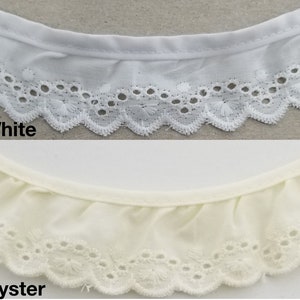 May include: Two samples of white eyelet lace trim. The top sample is white and the bottom sample is oyster.