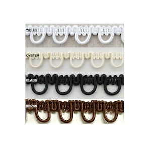 Pode incluir: Quatro amostras de guarnição decorativa em branco, ocre, preto e castanho. A guarnição tem uma borda festoneada.