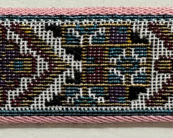 May include: A close-up of a pink and blue patterned fabric trim. The trim features a geometric design with black, white, gold, and blue accents.