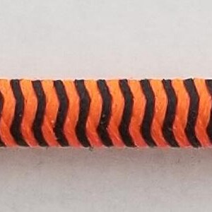 May include: A close-up of a black and orange striped cord.
