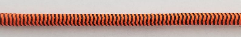 May include: A close-up of a black and orange striped cord.