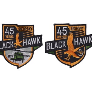 May include: Two black and gold embroidered patches celebrating 45 years of the Sikorsky Black Hawk helicopter. The patches feature a black hawk with a helicopter in the background. The text "45 Years" and "1978-2023" are included on the patches.