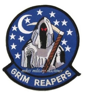 May include: A blue and white embroidered patch with a grim reaper figure holding a scythe. The patch has a crescent moon and stars in the background. The text "GRIM REAPERS" is written in white on a black banner.