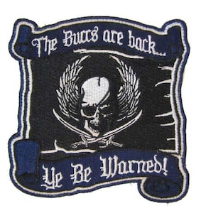 May include: Embroidered patch with a skull and crossed swords design. The patch is black with white and blue accents, and features the text "The Buccs are back... Ye Be Warned!"