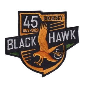May include: Black and green embroidered patch with a gold eagle, the text "BLACK HAWK" and "SIKORSKY" and the number "45" with the text "1978-2023".