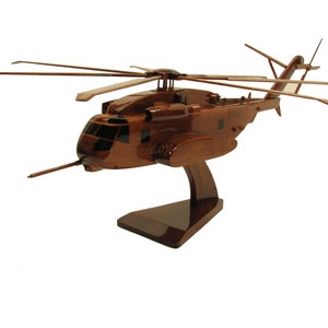 May include: A wooden model of a brown Sikorsky MH-60 Seahawk helicopter on a wooden stand. The helicopter has a detailed design and is a great addition to any aviation enthusiast's collection.