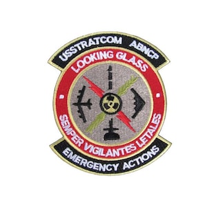 May include: A black, red, and gold embroidered patch with the text "USSTRATCOM ABNCP LOOKING GLASS SEMPER VIGILANTES LETALES EMERGENCY ACTIONS". The patch features a stylized image of a nuclear symbol, a lightning bolt, and aircraft.