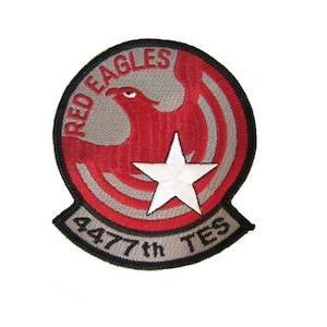 May include: A red, white, and gray embroidered patch with a red eagle and a white star. The text "RED EAGLES 447th TES" is around the edge of the patch.
