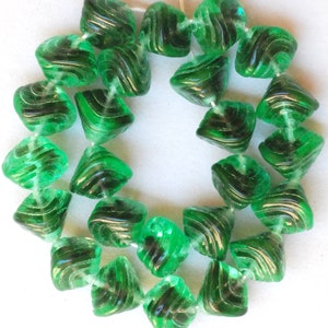 May include: A strand of green glass beads with a swirl design. The beads are faceted and have a translucent appearance.
