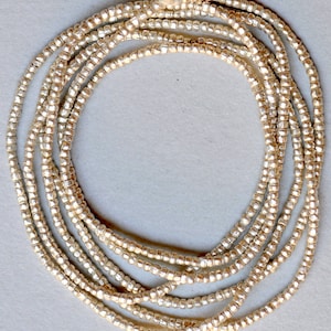 May include: A strand of silver-toned beads, arranged in a circle, on a white background.