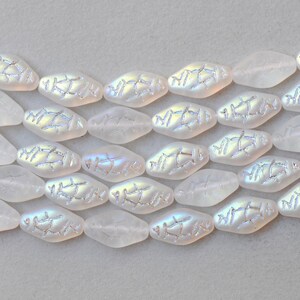 May include: Close-up of iridescent white oval beads with a textured, silver-colored design. The beads are arranged in rows, showcasing their unique shape and shimmering surface. Ideal for jewelry making.