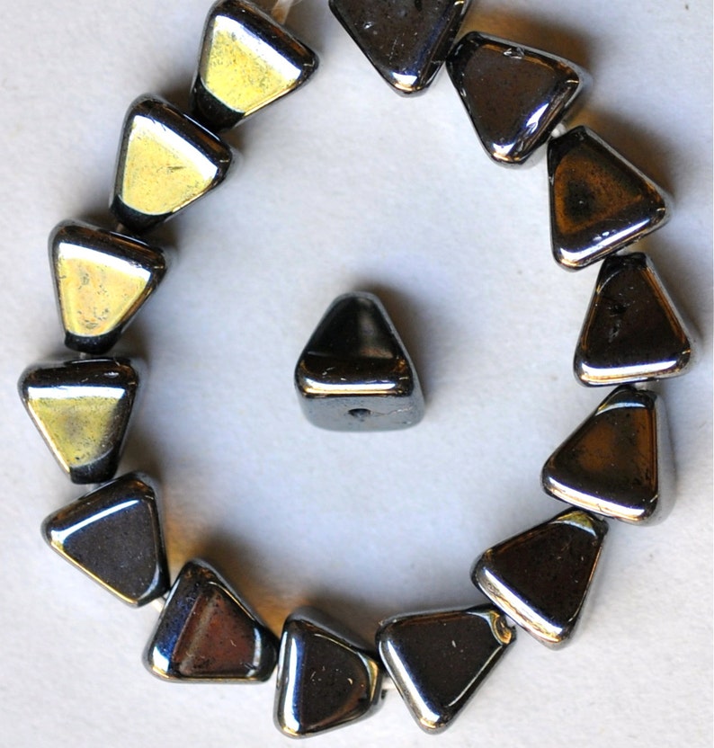 May include: A strand of black triangular glass beads with a single bead separated from the strand. The beads have a shiny, metallic finish.