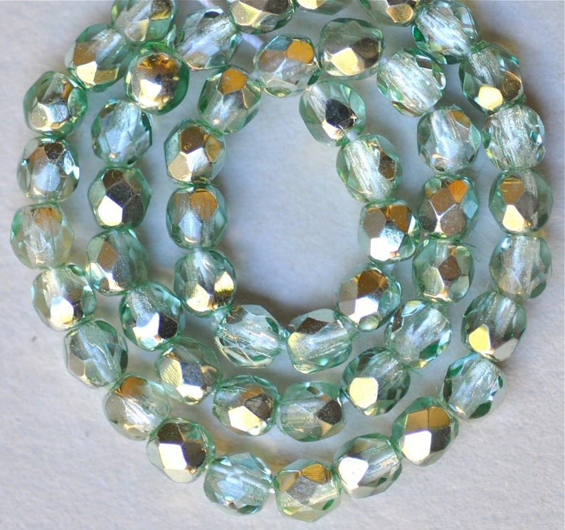 May include: A strand of light green faceted glass beads with a silver metallic finish.