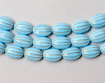 May include: A strand of oval-shaped glass beads with a light blue color and gold stripes. The beads are arranged in a row.