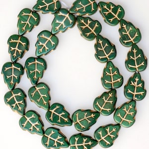 May include: A strand of green glass beads with gold leaf accents in the shape of leaves.