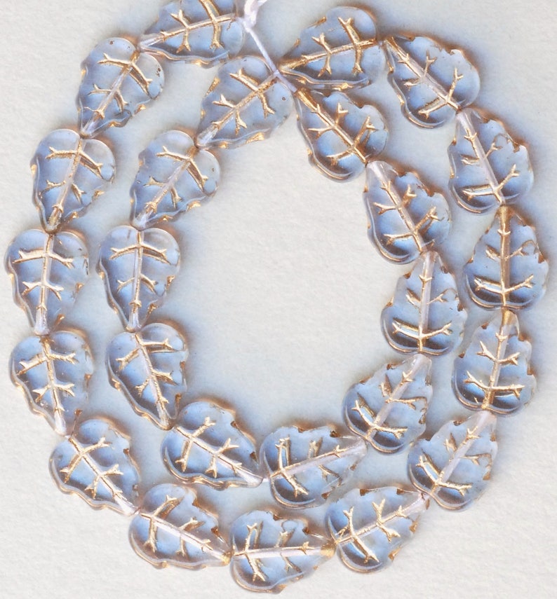 May include: A strand of light blue glass beads in the shape of leaves with gold accents.