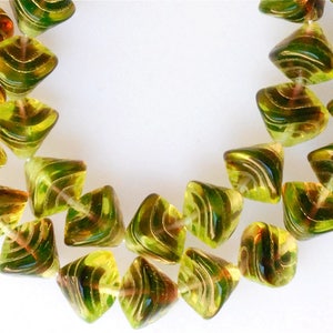 May include: A strand of green and gold glass beads. The beads are faceted and have a swirl pattern.