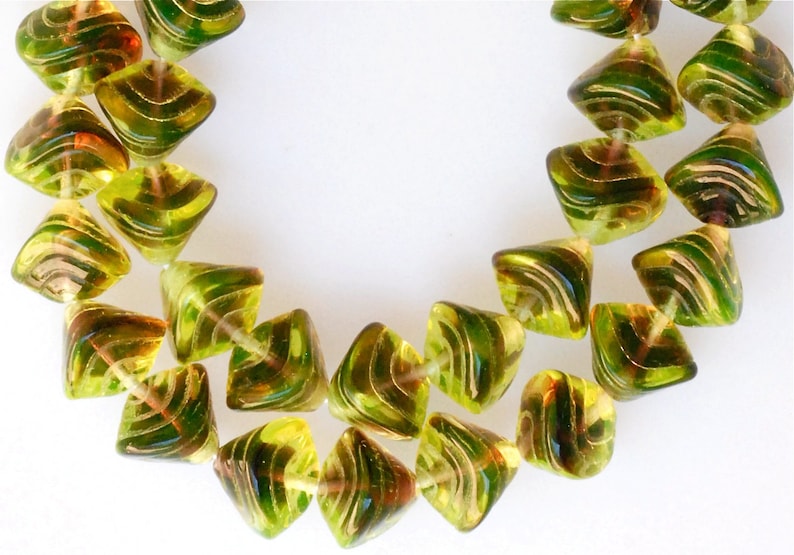 May include: A strand of green and gold glass beads. The beads are faceted and have a swirl pattern.