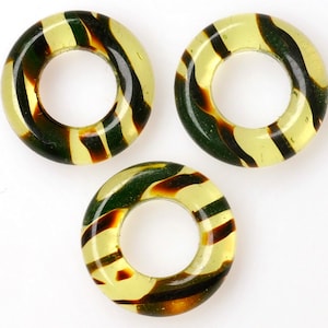 Puede incluir: Tres anillos de vidrio con rayas amarillas y marrones. Los anillos tienen un di&aacute;metro de aproximadamente 2,5 cm.