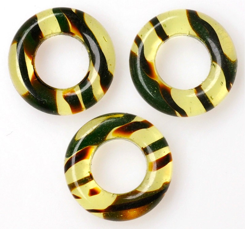 Puede incluir: Tres anillos de vidrio con rayas amarillas y marrones. Los anillos tienen un di&aacute;metro de aproximadamente 2,5 cm.