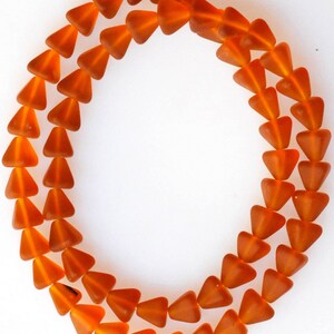 May include: A strand of orange glass beads in a triangle shape.