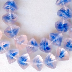 May include: A strand of light pink and blue glass beads. The beads are faceted and have a swirl design.