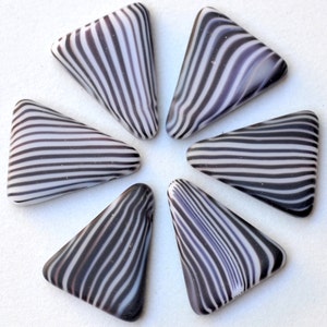 May include: Six black and white striped triangular shaped glass tiles arranged in a flower pattern.