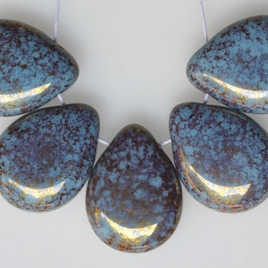 May include: Five teardrop-shaped beads strung on white thread. The beads have a speckled blue and brown pattern with a glossy finish. The beads are approximately 1 inch in length.