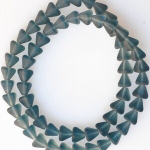 May include: A strand of teal blue glass triangle beads. The beads are faceted and have a frosted finish.