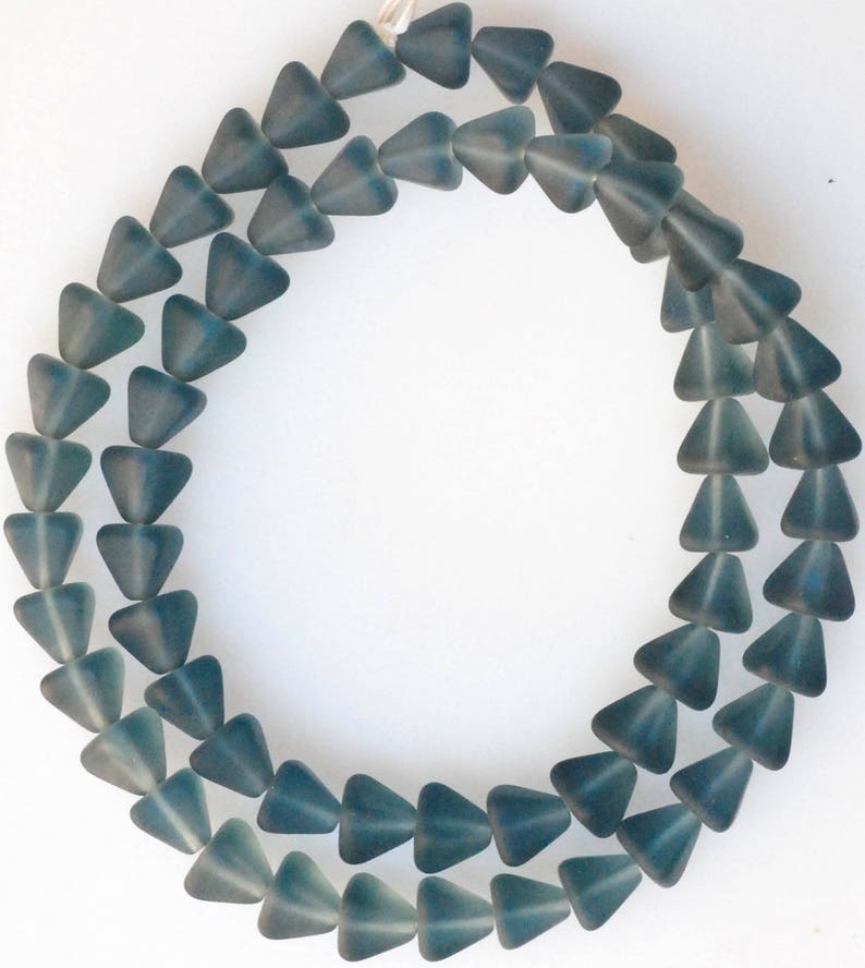 May include: A strand of teal blue glass triangle beads. The beads are faceted and have a frosted finish.