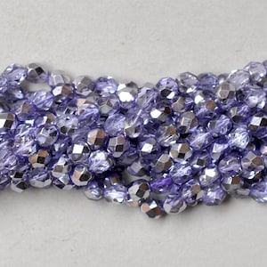 May include: A strand of iridescent purple glass beads with a faceted finish. The beads are small and round, and they have a metallic sheen.
