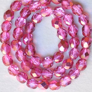 May include: A strand of pink faceted glass beads with a metallic sheen. The beads are strung on a clear thread and are approximately 8mm in diameter.