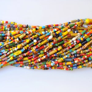 May include: A large collection of colorful glass beads in various shapes and sizes. The beads are mostly yellow, red, blue, and green.