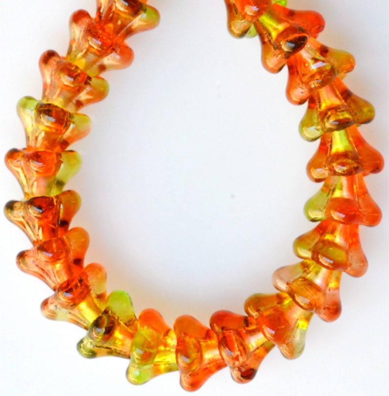 Puede incluir: Una hebra de cuentas de vidrio naranja y verde en forma de flor. Las cuentas est&aacute;n enhebradas para formar un collar o una pulsera.