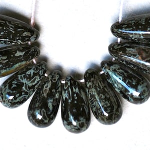 May include: A strand of ten teardrop-shaped beads with a black and green marbled pattern.